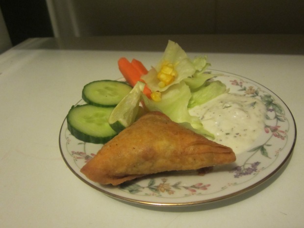 One Samosa on my plate with salad and a serving of yogurt